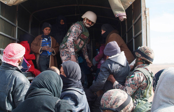 Border Guards personnel assist newly arrived Syrian refugees in this undated photo (Petra photo)